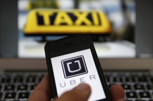 A file illustration picture shows the logo of car-sharing service app Uber on a smartphone next to the picture of an official German taxi sign in Frankfurt, September 15, 2014. A German court is set to rule March 18, 2015, whether Uber's novel taxi-hailing service violates driver licensing rules, a decision that could lead to a nationwide ban on the service. The case in a Frankfurt court brought by German taxi operator group Taxi Deutschland against Uber is one of more than a dozen lawsuits filed across Europe in recent months by taxi industry associations against the San Francisco-based company. Taxi drivers around the world consider Uber unfairly bypasses local licensing and safety regulations by using the internet to put drivers in touch with passengers. REUTERS/Kai Pfaffenbach/Files (GERMANY - Tags: BUSINESS EMPLOYMENT CRIME LAW TRANSPORT)